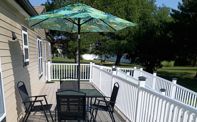 Outdoor deck with a patio table and green umbrella.